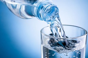 21036145 - pouring water from bottle into glass on blue background