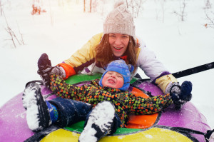 69070359 - happy smiling mother and child sit on snow tube
