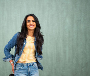 Close up smiling young North African woman posing by green wall