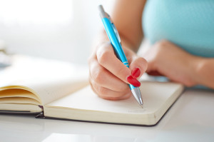 30502332 - young woman writes to black diary on a white table