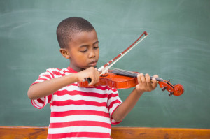 Cute pupil playing violin in classroom at the elementary school